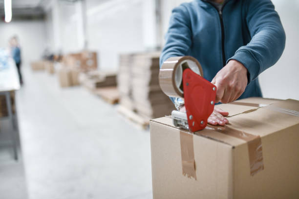 Male Worker Taping Cardboard Box
