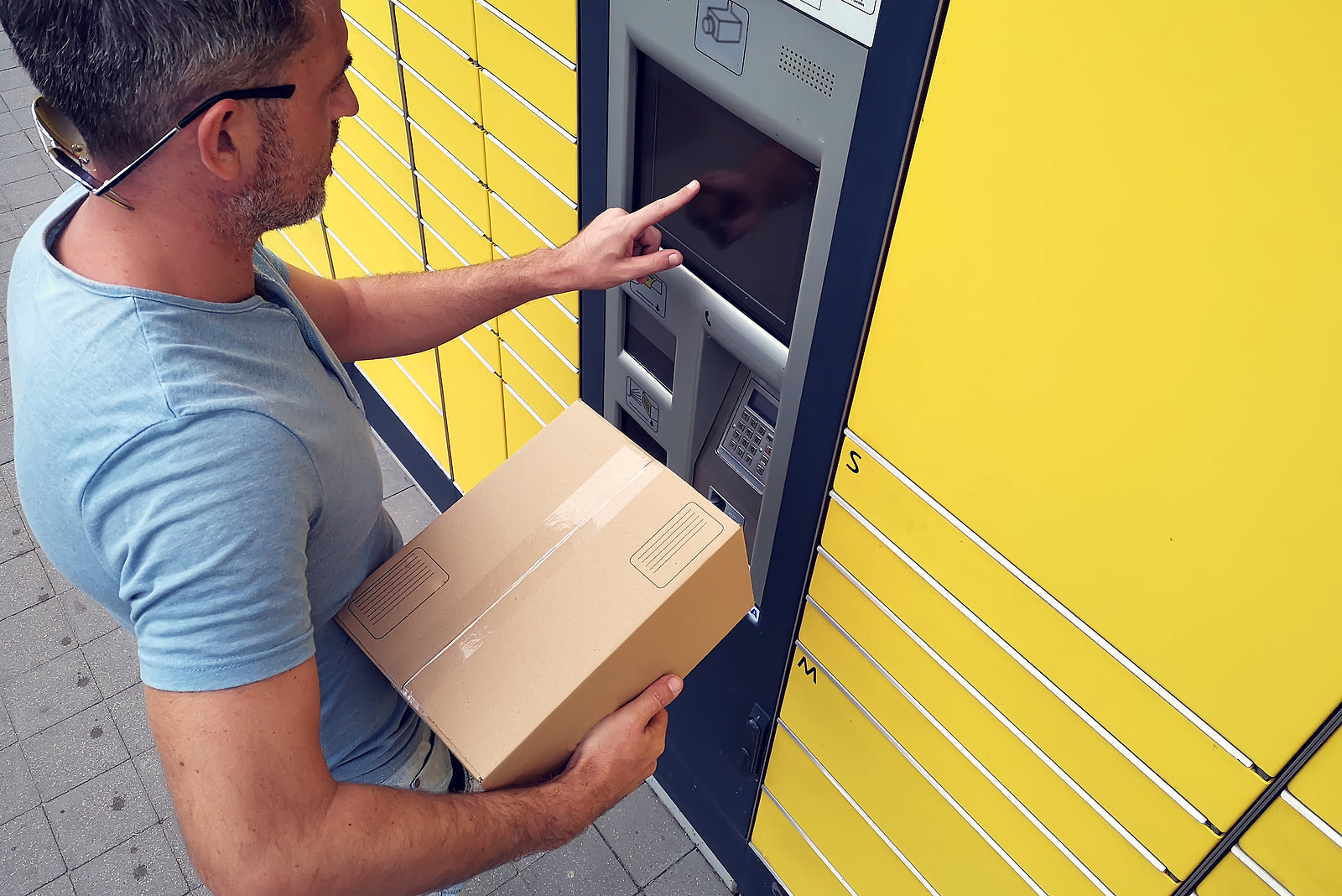 custom cardboard boxes - Man using automated self service post terminal machine
